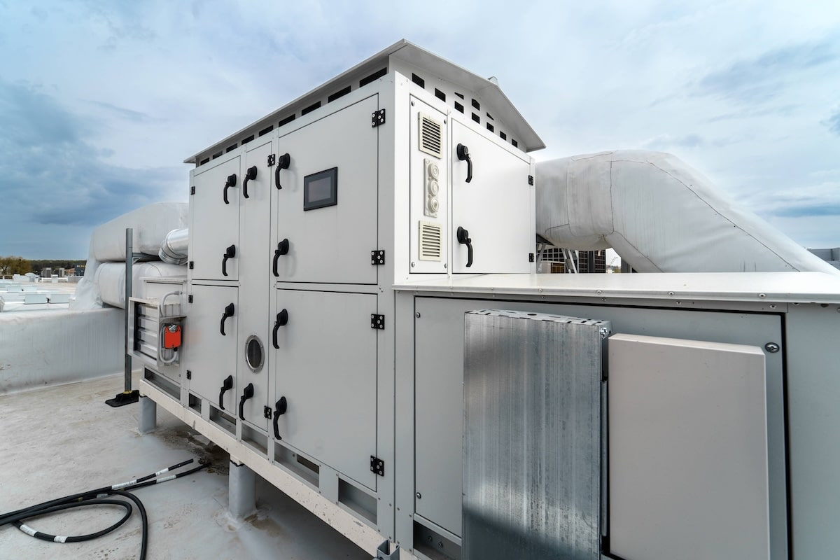 A large industrial HVAC unit with control panels and insulated ductwork installed on a building's rooftop.