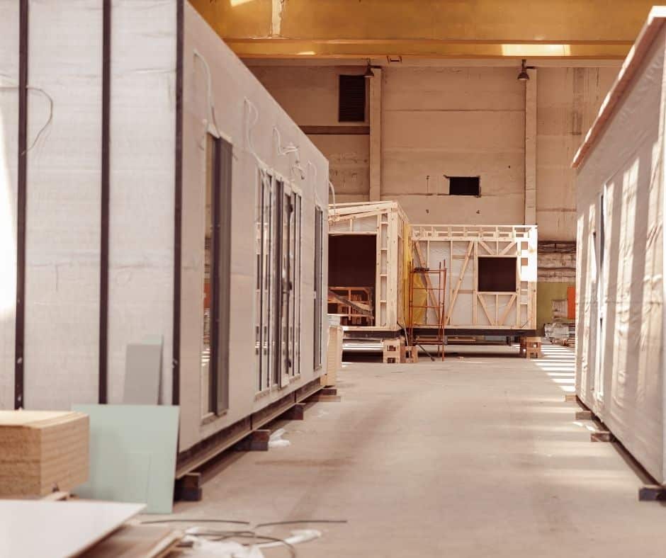 Prefabricated manufactured home modules under construction inside a large factory facility